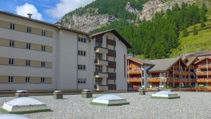 A hotel with a modern design, featuring multiple floors and a prominent mountain backdrop. - Viktoria B by Interhome (Zermatt)