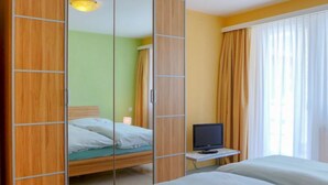 A hotel room with a bed, a television on a small table, and a mirror cabinet. - Viktoria B by Interhome (Zermatt)