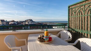 Une terrasse avec une table préparée pour le petit-déjeuner, donnant sur une ville côtière.
