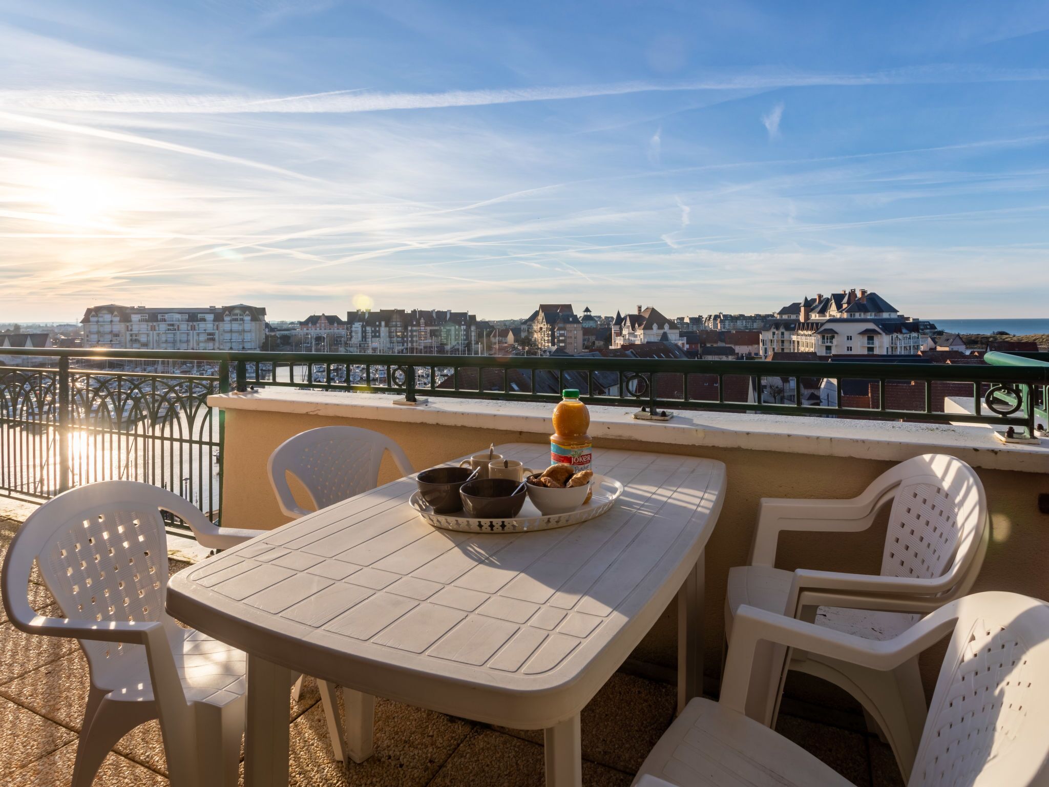 En terrasse med et bord dækket til to, stole og udsigt over en kystby.