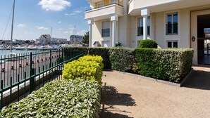 Un immeuble à plusieurs étages doté de balcons, une marina avec des bateaux et un ciel dégagé.