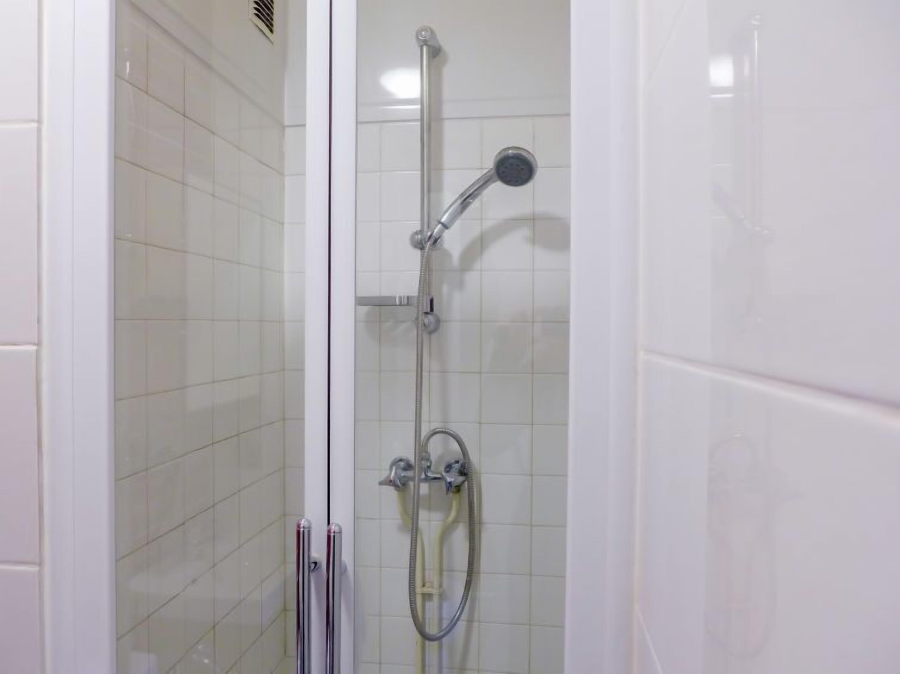 A shower with a handheld showerhead and a wall-mounted faucet.