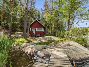 Une cabane avec un quai donnant sur un ruisseau, entourée d’arbres.