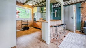A modern kitchen with wooden cabinets, a built-in microwave, and a window overlooking a green landscape.