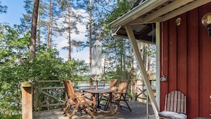 A wooden deck with a table and chairs, surrounded by trees.