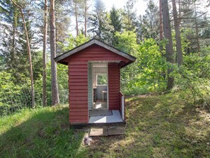 A small, single-room cabin with a door and a window, surrounded by a forest. - Artturin mökki by Interhome (Kirkkonummi)
