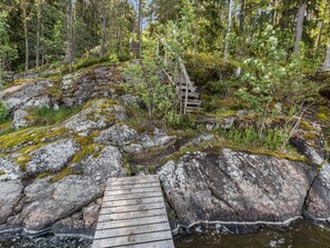 Eine Holzbrücke über einen felsigen Bach mit moosbewachsenen Steinen und dichtem Wald im Hintergrund.