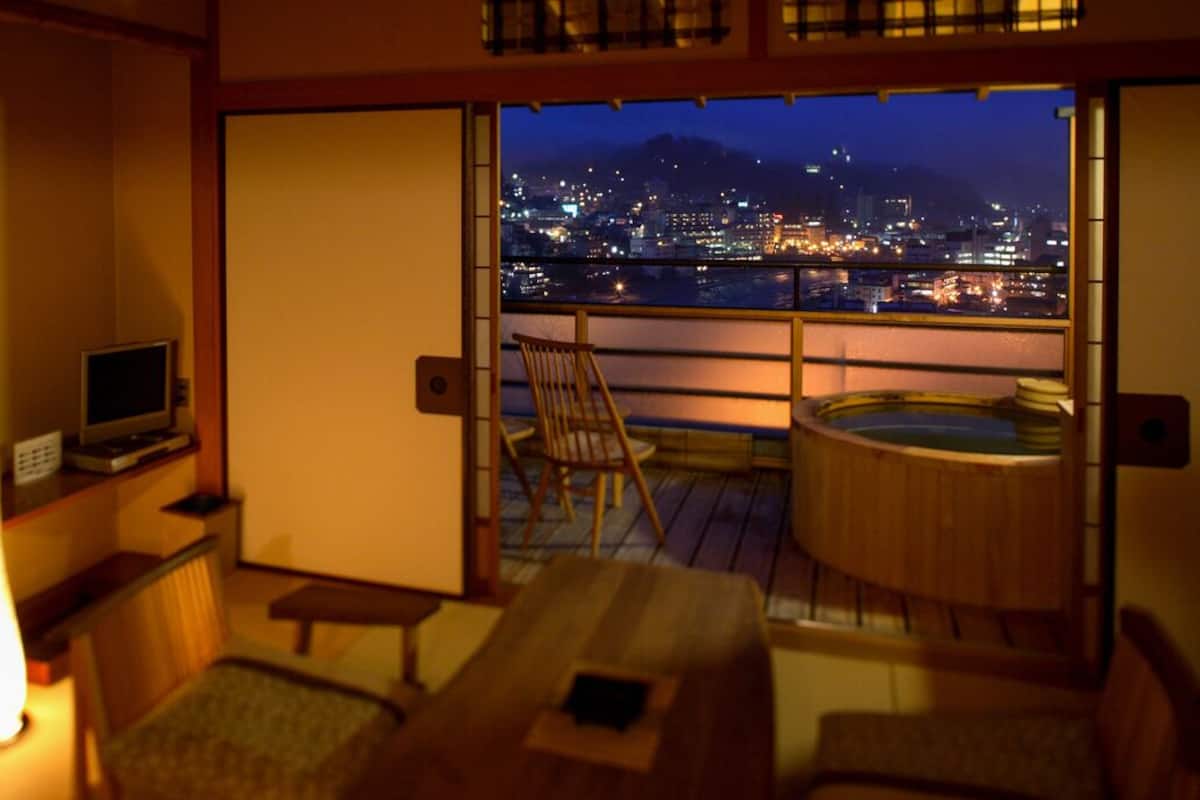 A room with a city view, a hot tub, a TV, and a traditional Japanese sliding door.