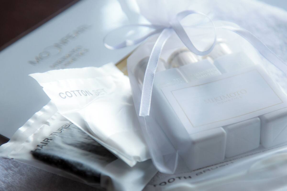 Eine Packung mit weißem Band, beschriftet mit 'Mikimoto Cosmetics', und einem Anhänger mit der Aufschrift 'Cotton Set'.