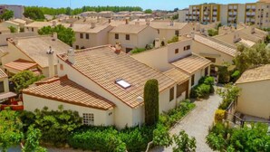 Un barrio residencial con tejados de tejas terracota, paredes blancas y abundante vegetación.