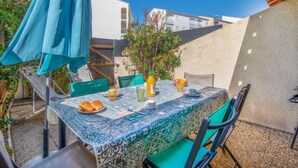 Un patio con una mesa dispuesta para el desayuno, incluyendo pan, fruta y bebidas.