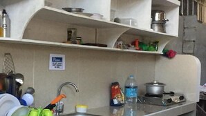 A compact kitchen with a sink, a stove, and shelves above for storage. - Maharlika Siargao (General Luna)