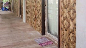 A covered corridor with patterned wooden walls and a door with a glass panel. - Maharlika Siargao (General Luna)