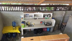 A compact kitchen with a sink, shelves, and a table. - Maharlika Siargao (General Luna)
