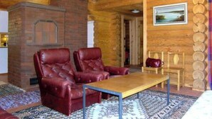 A cozy room with a fireplace, leather chairs, a wooden table, and a view of the outdoors. - Metsämarja by Interhome (Kemiönsaari)