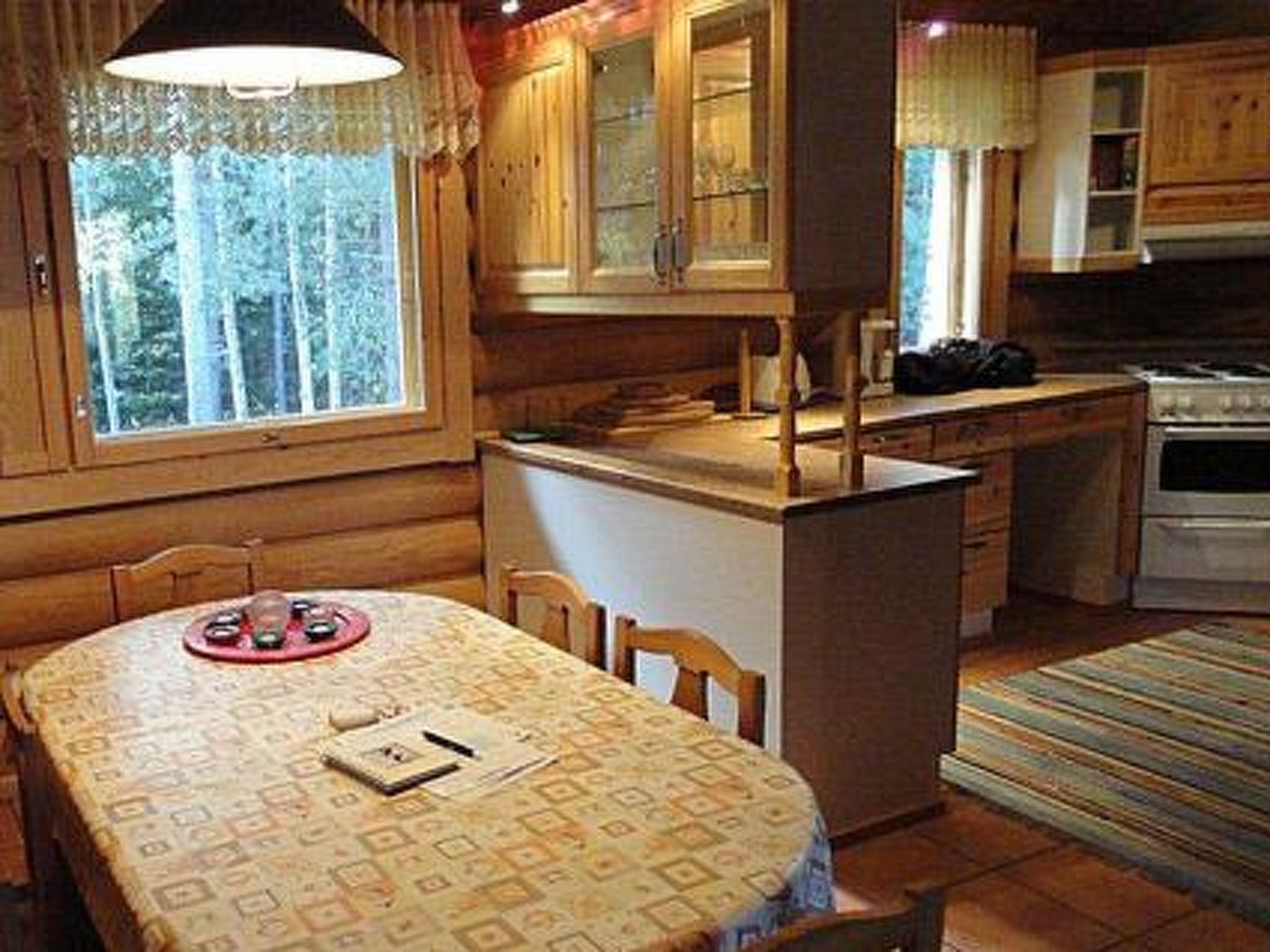 A cozy cabin interior with a dining area, kitchen, and a large window.