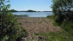 A sandy beach with a clear view of a lake and a distant island. - Metsämarja by Interhome (Kemiönsaari)