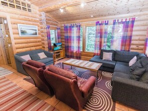 A log cabin interior with a sofa set, a television, and a window with curtains. - Metsämarja by Interhome (Kemiönsaari)