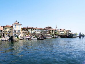 Waterfront buildings with traditional architecture and balconies line the calm water's edge.