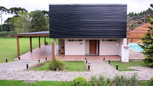 Ein modernes Gebäude mit flachem Dach, einer überdachten Terrasse und einem Swimmingpool.
