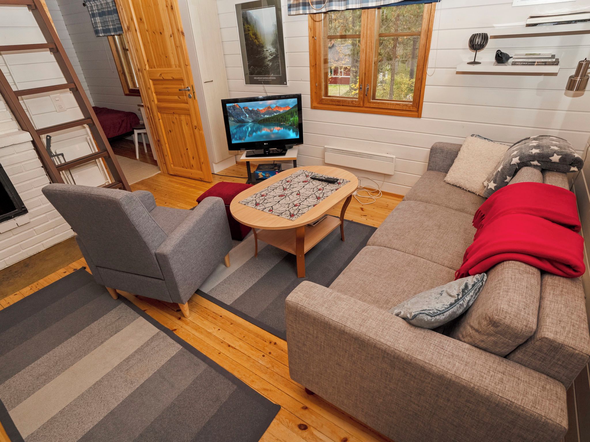 Una sala de estar acogedora con un sofá, sillas, un televisor y un ventanal con vistas.