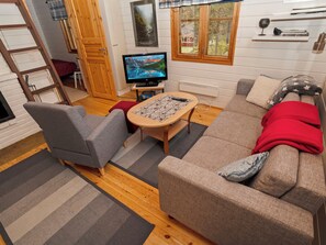 Una sala de estar acogedora con un sofá, sillas, un televisor y un ventanal con vistas.