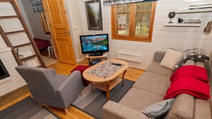 En hyggelig stue med sofa, lænestole, sofabord og fjernsyn.
