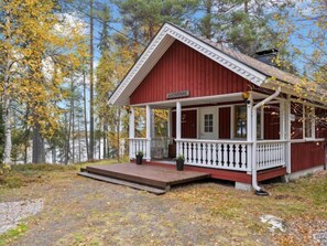 Surrounded by a forest, this cabin features a cozy porch and a small deck.