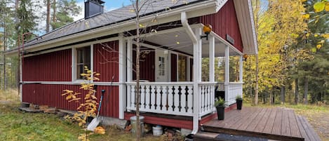 En röd trästuga med en vit veranda och en liten terrass.