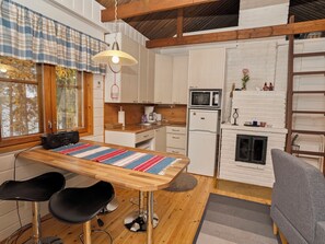A compact kitchen with a wooden table, bar stools, a microwave, and a refrigerator.