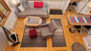 A compact living space with a sofa, armchair, coffee table, and a small dining area.