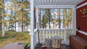 En træterrasse med gelænder, bænk og lille bord.