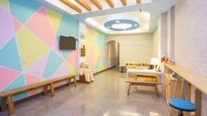 A brightly colored children's playroom with a wooden bench, a teddy bear, and a table with toys. - Green Stay (Hengchun)