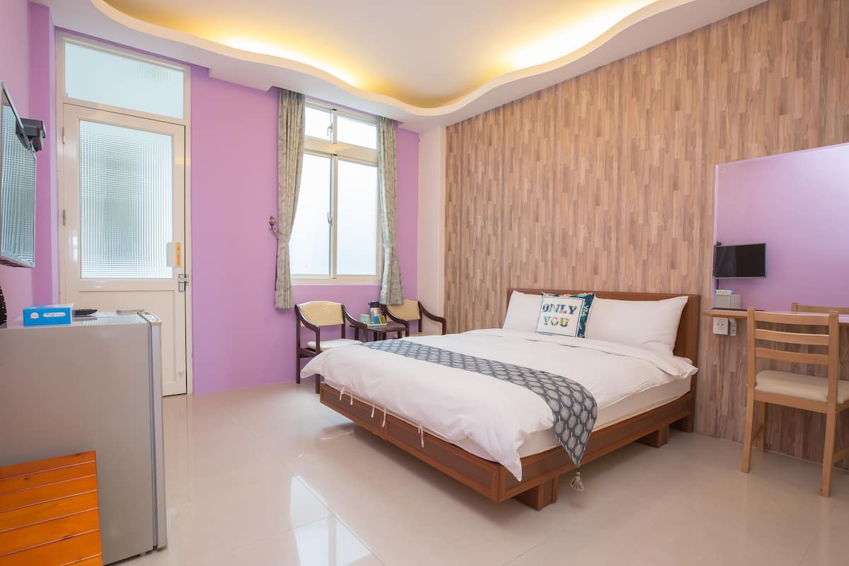 A modern bedroom with a wooden bed, a desk, and a chair.