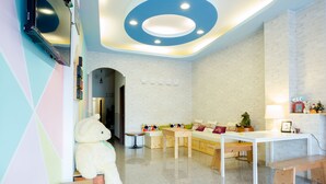 A children's playroom with a large teddy bear, a play table, and a sofa with colorful cushions. - Green Stay (Hengchun)