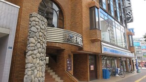 A hotel with a stone pillar, a staircase, and a sign with Chinese characters. - Sapporo Met S (Sapporo)