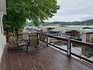 Une terrasse en bois avec des sièges extérieurs, offrant une vue sur une marina avec des bateaux et des quais.