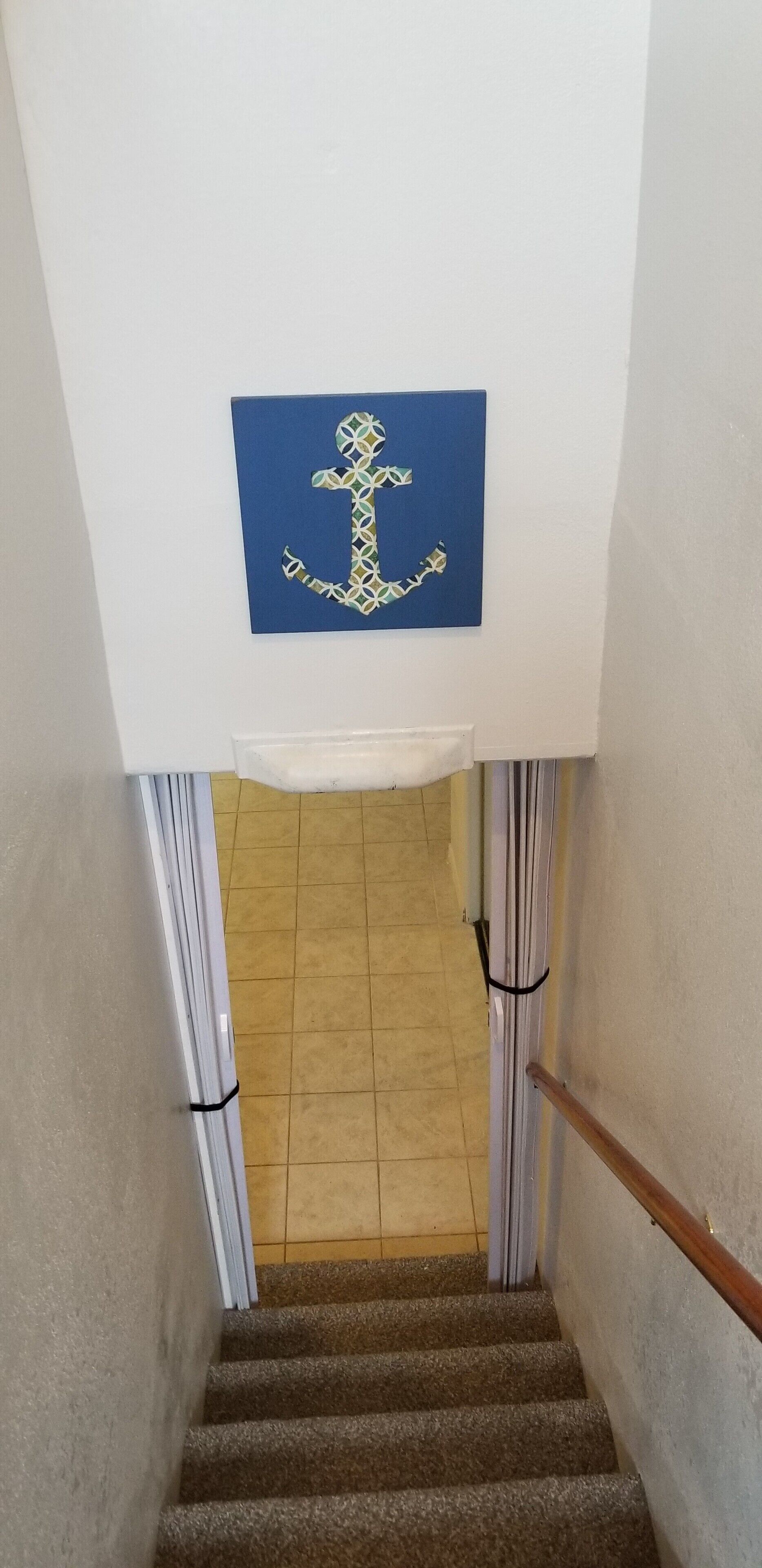 Eine Treppe mit einer blauen Wand darüber, die zu einem Raum mit Fliesenboden führt.