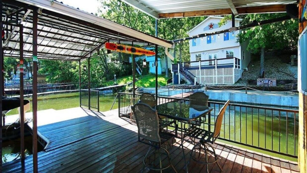 Une terrasse extérieure couverte avec une piscine, une table et des chaises, et une maison en arrière-plan.