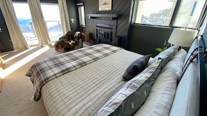 Een moderne slaapkamer met een groot bed, een open haard en uitzicht op de stad.