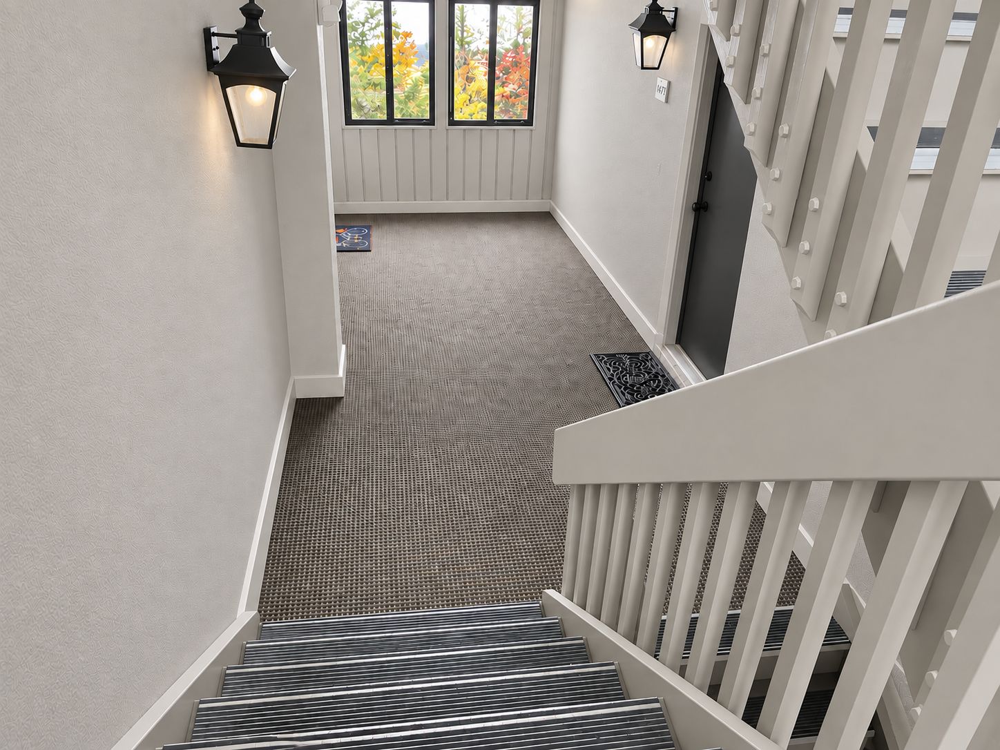 Un escalier recouvert d’une moquette à motifs menant à un palier doté d’une porte et de fenêtres.