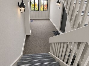 A staircase with a textured carpet leading to a landing with a door and windows.