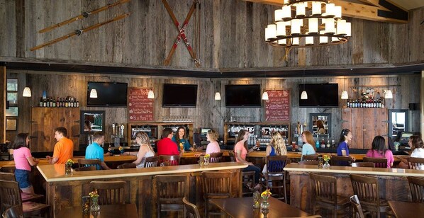 A bar area with wooden walls, multiple TVs, and a variety of seating arrangements.