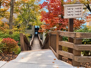 A wooden staircase leading to a building with a sign displaying apartment numbers.