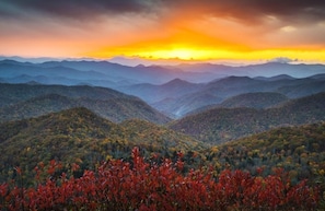 A mountainous landscape with autumn foliage and a sunset.