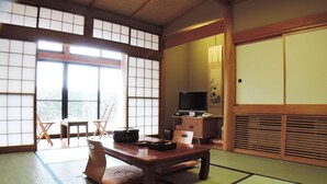 A tatami mat room with a low table, a television, and traditional Japanese furniture. - Kurion (Senboku)