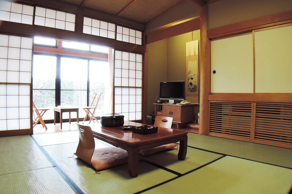 A tatami mat room with a low table, a television, and traditional Japanese furniture.