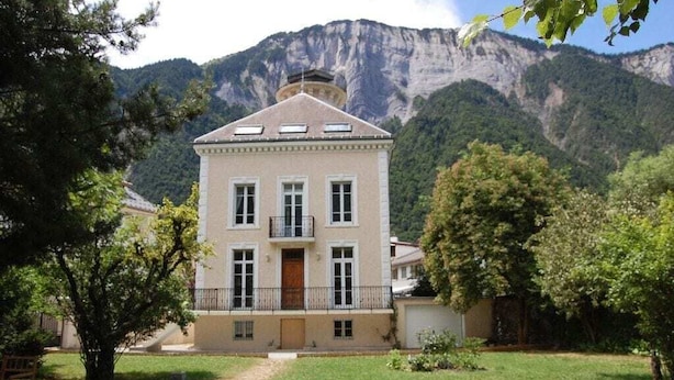A two-story building with a symmetrical facade, a central entrance, and a balcony. - STUNNING FRENCH HOUSE, SPACIOUS AND WELL EQUIPPED - SLEEPS 10 (Le Bourg-d'Oisans)