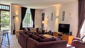 A living room with a large sectional sofa, a flat-screen TV, and a dining area with a table and chairs. - STUNNING FRENCH HOUSE, SPACIOUS AND WELL EQUIPPED - SLEEPS 10 (Le Bourg-d'Oisans)