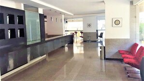 A modern lobby with a reception desk, seating area, and framed artwork on the walls. - Sea view Serviced Apartment 2 bedroom 2 bath #1 (Hawally)